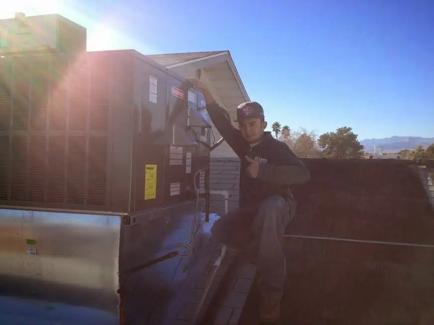 HVAC technician performing HVAC Inspection on a rooftop unit in Geddes